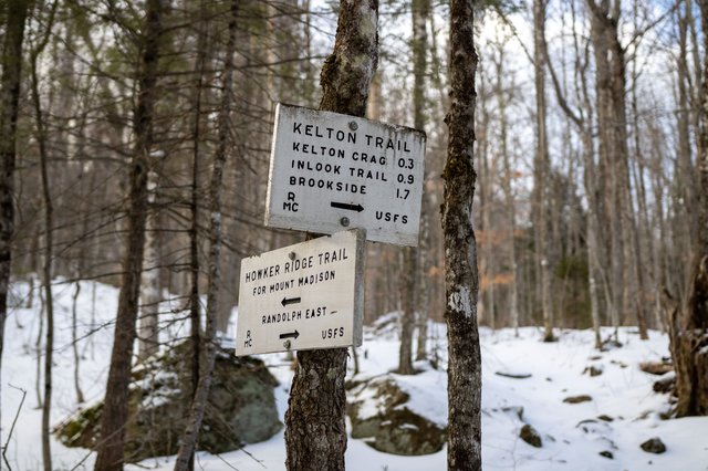 Kelton Trail junction sign standing among snow‑covered trees.